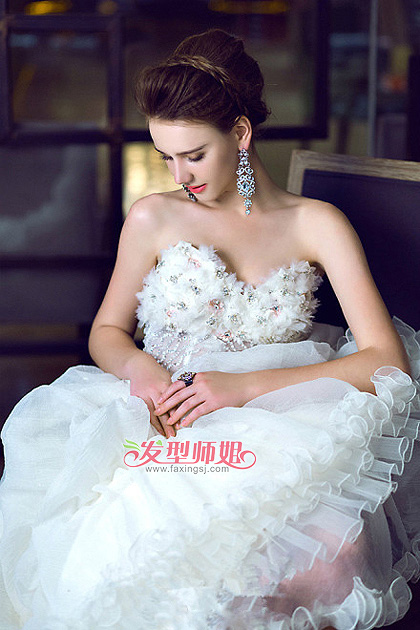 制造出蓬松的立体感,从视觉上看拉长了新娘的身高,也唯美的修饰了脸型,蓬松充满空气感的新娘发型在搭配珍珠网纱的面纱,精致迷人的妆容,一款抹胸婚纱加身,其优雅迷人的气质不言而喻。 Style 2 这款欧美风的新娘盘发与第一款发型略有相似之处,同样的盘发造型搭配不一样的发饰,打造出不一样的优雅气质感,心动的新娘子在自己结婚那天可以多换几款发饰哦!争取找到最适合自己的。